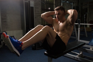 Naklejka premium young man doing sit-up abdominal exercises in gym