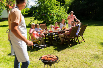 man cooking meat on barbecue grill at summer party