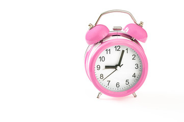 Vintage pink alarm clock, with 3 minutes past 9 o'clock on it. Isolated on white background. Close up