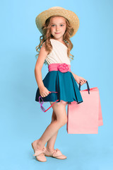 The cute little caucasian brunette girl in dress holding shopping bags