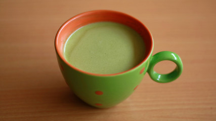 Cup of matcha green tea latte with wood background.