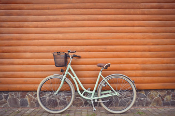 Close up of blue retro vintage bicycle with basket on wooden wall background. Urban lifestyle. Copy space.