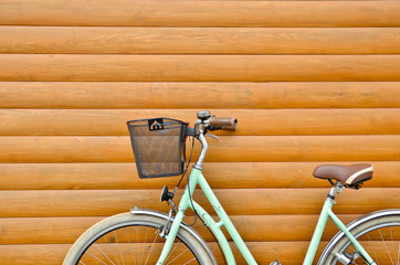 Close up of blue retro vintage bicycle with basket on wooden wall background. Urban lifestyle. Copy...