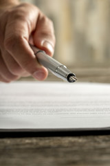 Male hand holding ink pen offering you to sign a document or contract