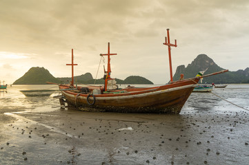 Naklejka na ściany i meble fishing boat on the beach with sea and sunrise background