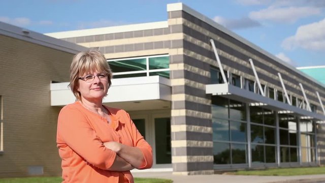 High School Teacher turns and smiles at Camera near High School