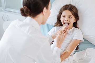 Obraz na płótnie Canvas Pleasant cheerful girl being examined by a doctor
