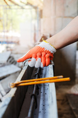 Close up of workers hands using pincers bind steel wire to rebar before concrete is poured over it.