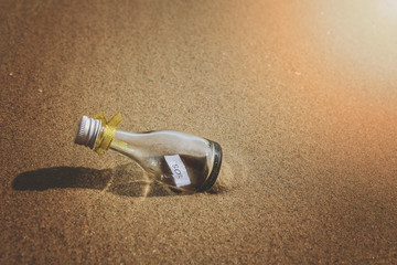 SOS message in glass bottle on the beach.