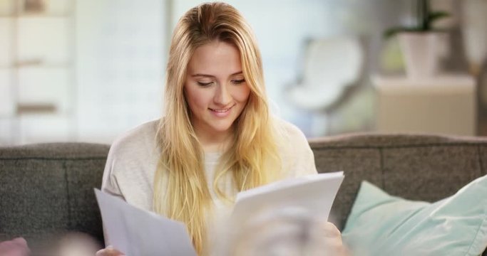 Happy young woman reading a letter at home