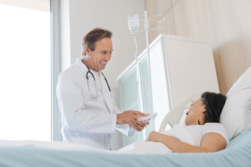 Obraz premium Handsome positive doctor talking to his patient