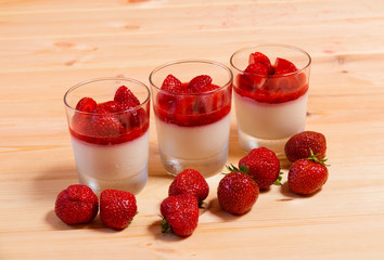 Delicious italian dessert panna cotta with strawberry coulis served in small transparent glasses. Selective focus