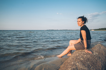 woman sits on the rock and lookin for lake view