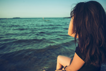 Naklejka premium woman sits on the rock and lookin for lake view
