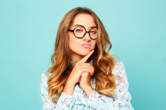 Portrait of a thoughtful girl wearing glasses. Pretty student over blue background