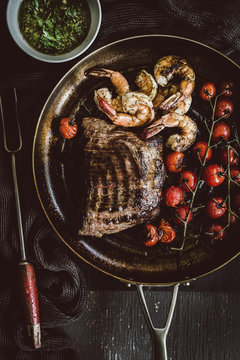 Steak, shrimp and cherry tomatoes on frying pan