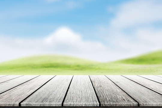 Wood table top on blurred mound slope green grass natural background in morning time.