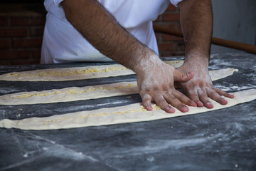 Men's hands prepare pizza dough on a marble table