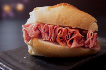 Mortadella sandwich on dark background. Traditional food of Sao Paulo Brazil. Selective focus.