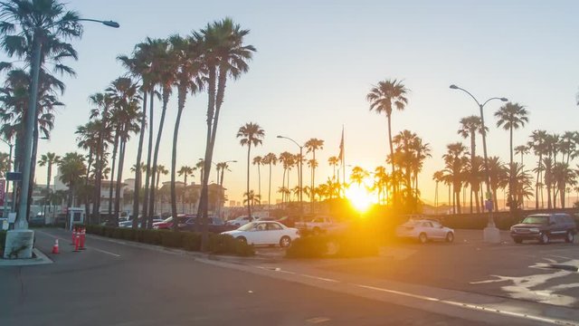 Cinematic 4K urban timelapse in motion or hyperlapse in Southern California on a stunning early morning sunrise facing the city with palm trees and cars in the parking lot.