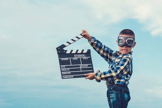 Kid Playing Film Clapper Board Against Summer Sky Background. Film Director Concept.
