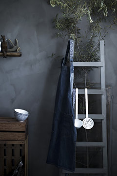 A rustic vintage kitchen with bowls, apron and utensils on a gray background