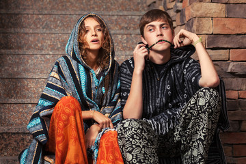 Young fashion hippie couple sitting on the steps