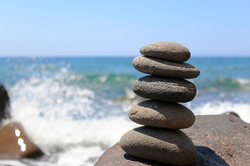 Smooth Stones Stacked on Top of Each Other on a  Greek Island Beach with Waves Breaking