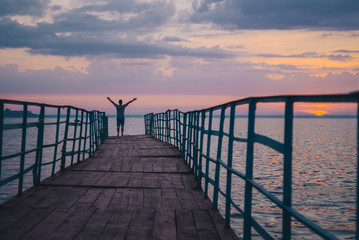Fototapeta premium man standing on the pier and looking on sunset