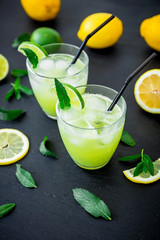 Fresh citrus refreshing lemonade with limes, ice and lemons in glasses