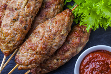 Lulya-kebab. Shish kebab on a stick, minced meat. Traditional Caucasian dish. With green salad, ketchup, spices.
