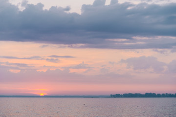 Beautiful blazing sunset landscape at black sea and orange sky above it with awesome sun golden reflection on calm waves as a background. Amazing summer sunset view on the beach.