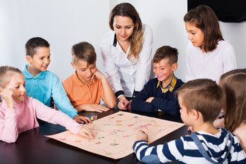 Boys and little girls playing at board game
