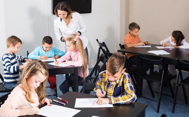 Little smiling children with teacher drawing in classroom
