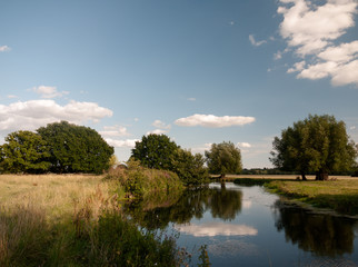 Fototapeta na wymiar river stour running through dedham countryside with clear sky and lush trees on a summer's day