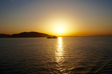 a sunrise on the Aegean sea , while a ship cross the sun's golden path !