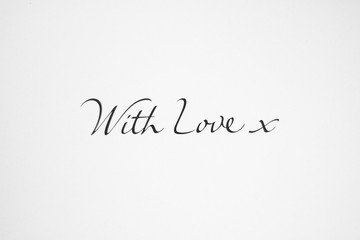 A text ‘With Love x’. This two words and a sign of hug wrote in the middle of a white sheet. It may be declaration of love and a background for your creativity.