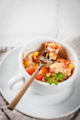 Trendy modern food, fast food, lunch in the microwave. Pizza in a mug, with ham, tomatoes, mushrooms, cheese. White cup, with a fork, on a white marble table. Copy space