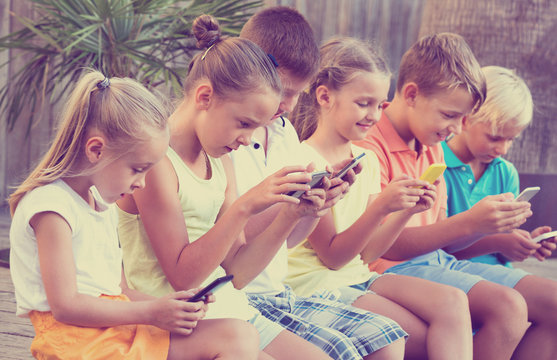 Busy children holding smartphones  and sitting