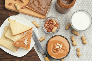 Composition with delicious peanut butter, toasts and glass of milk on table