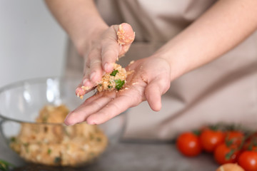 Young woman cooking turkey meatballs in kitchen