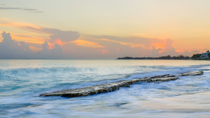 Sunset over a flat rock formation in the Caribbean sea at Cemetery Beach, Grand Cayman, Cayman Islands