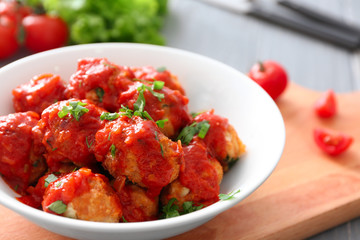 Bowl with delicious turkey meatballs and tomato sauce on table