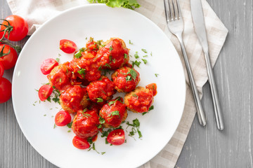 Plate with delicious turkey meatballs and tomato sauce on wooden table