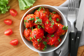 Bowl with delicious turkey meatballs and tomato sauce on wooden table