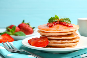 Plate with delicious pancakes on table