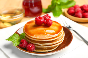 Plate with delicious pancakes on table