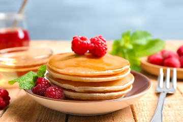Plate with delicious pancakes on table