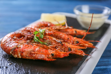 Slate plate with delicious shrimps on table