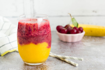 Colorful smoothie with two layers. Fruits in background.